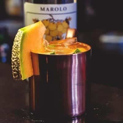 Cocktail nella coppa di rame con melone, grappa, ginger beer, bitter al cetriolo