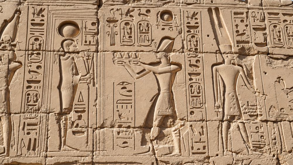 Karnak temple heiroglyphic pharaoh and god carving on sandstone wall